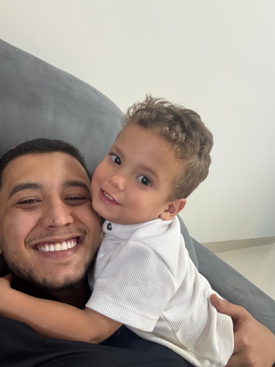 Foto comum de um pai abraçado com o filho no sofá